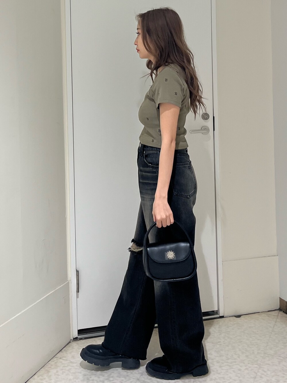 グリーン系のTシャツ/カットソー、ブラック系のブーツ、ブラック系のハンドバッグを着用したレディースの春コーディネートの2枚目の写真