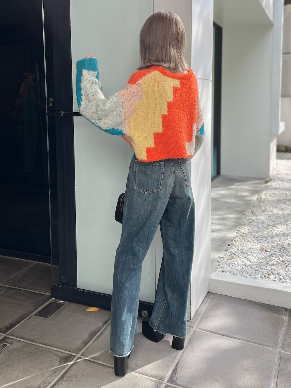 ブラック系のボストンバッグ、ブルー系のニット/セーター、ブルー系のデニムパンツを着用したレディースの冬コーディネートの3枚目の写真