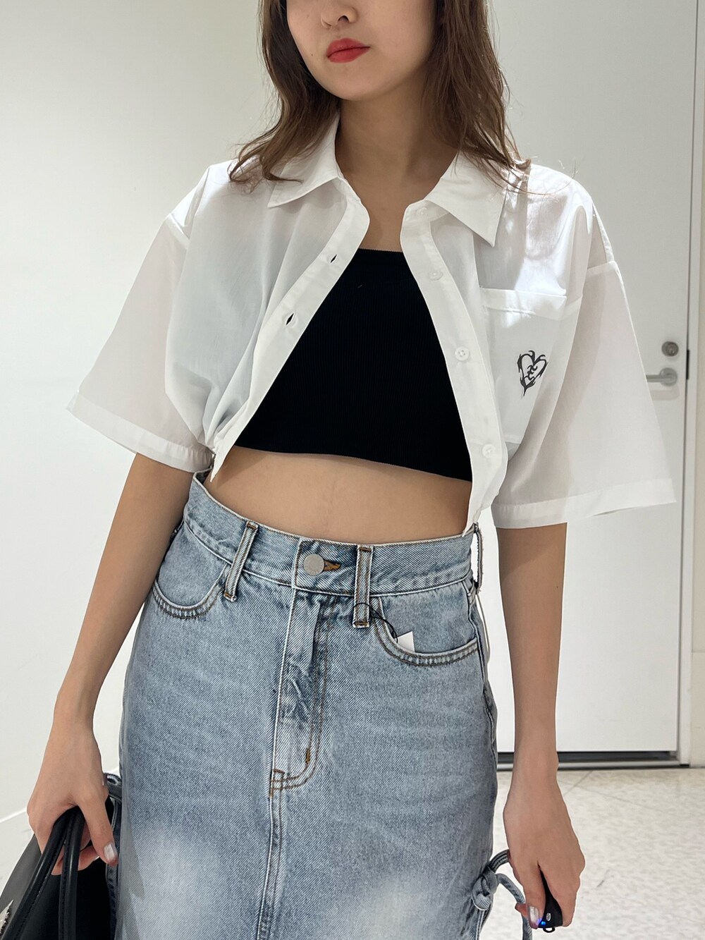 ブラック系のブーツ、ブルー系のデニムスカート、ブラック系のハンドバッグを着用したレディースの春コーディネートの5枚目の写真