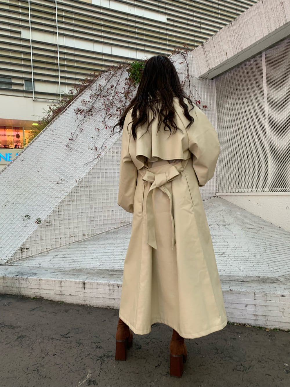 ブラウン系のブーツ、ベージュ系のTシャツ/カットソー、ホワイト系のトレンチコートを着用したレディースの冬コーディネートの2枚目の写真