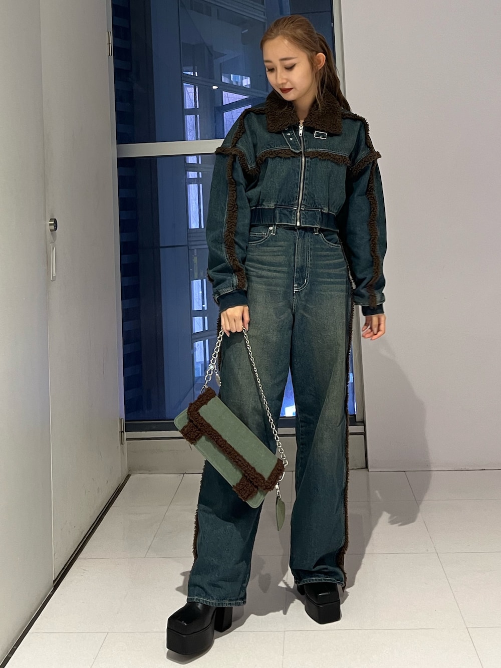 ブルー系のブルゾン、ブルー系のデニムパンツ、ブラック系のブーツを着用したレディースの秋コーディネートの3枚目の写真