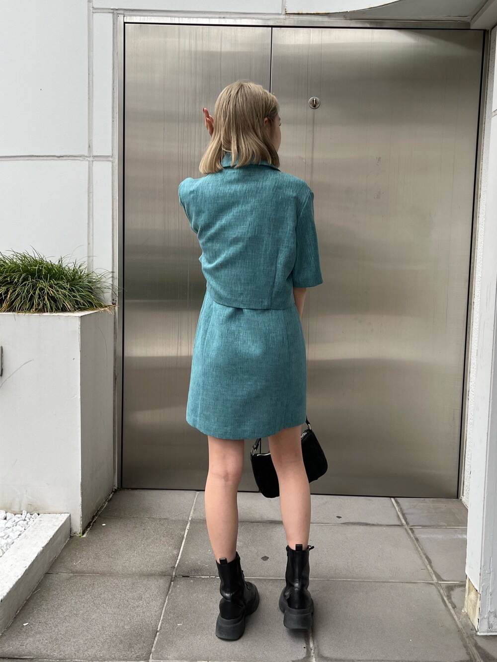 ブルー系のワンピース、グリーン系のテーラードジャケット、ホワイト系のブーツを着用したレディースの春コーディネートの3枚目の写真