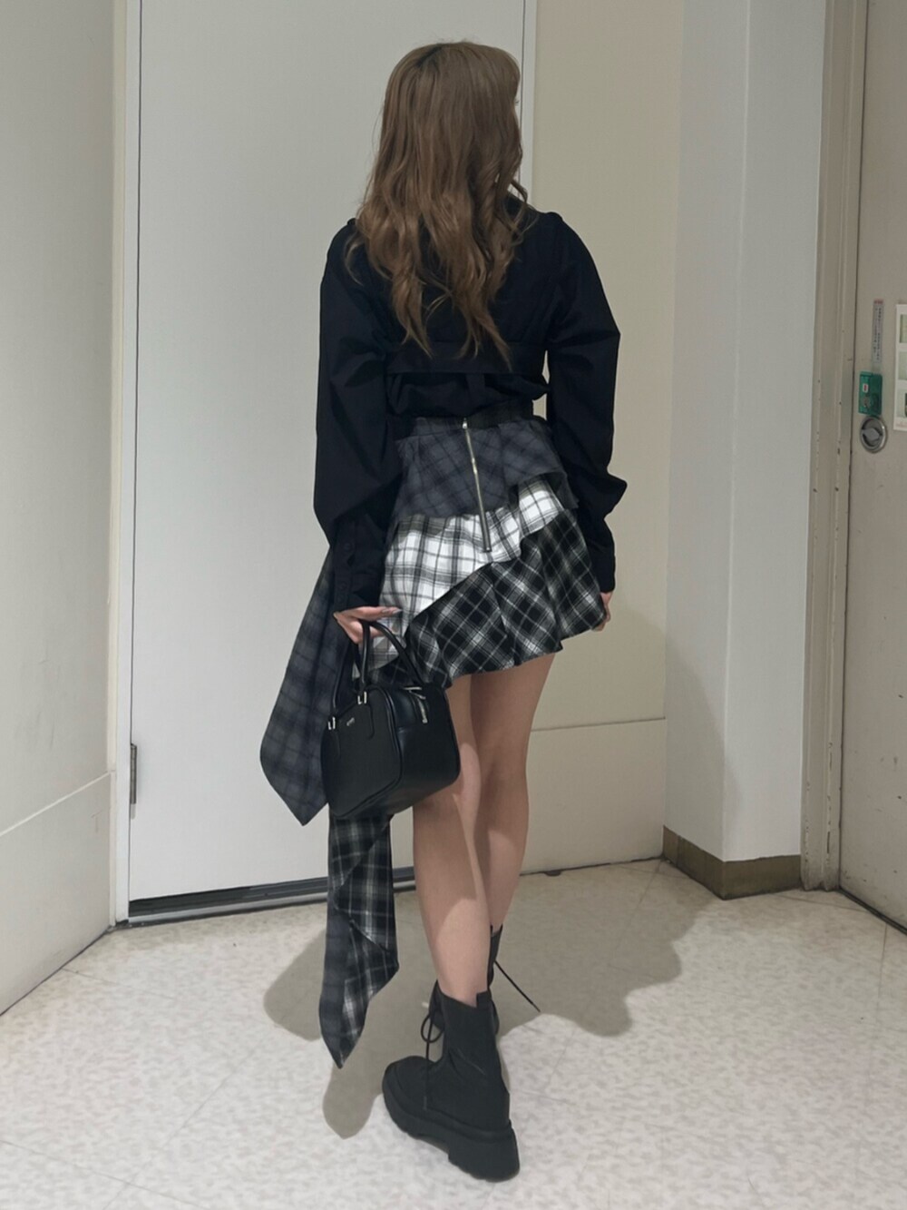 ブラック系のブーツ、ブラック系のボストンバッグ、ブラック系のスカートを着用したレディースの春コーディネートの3枚目の写真