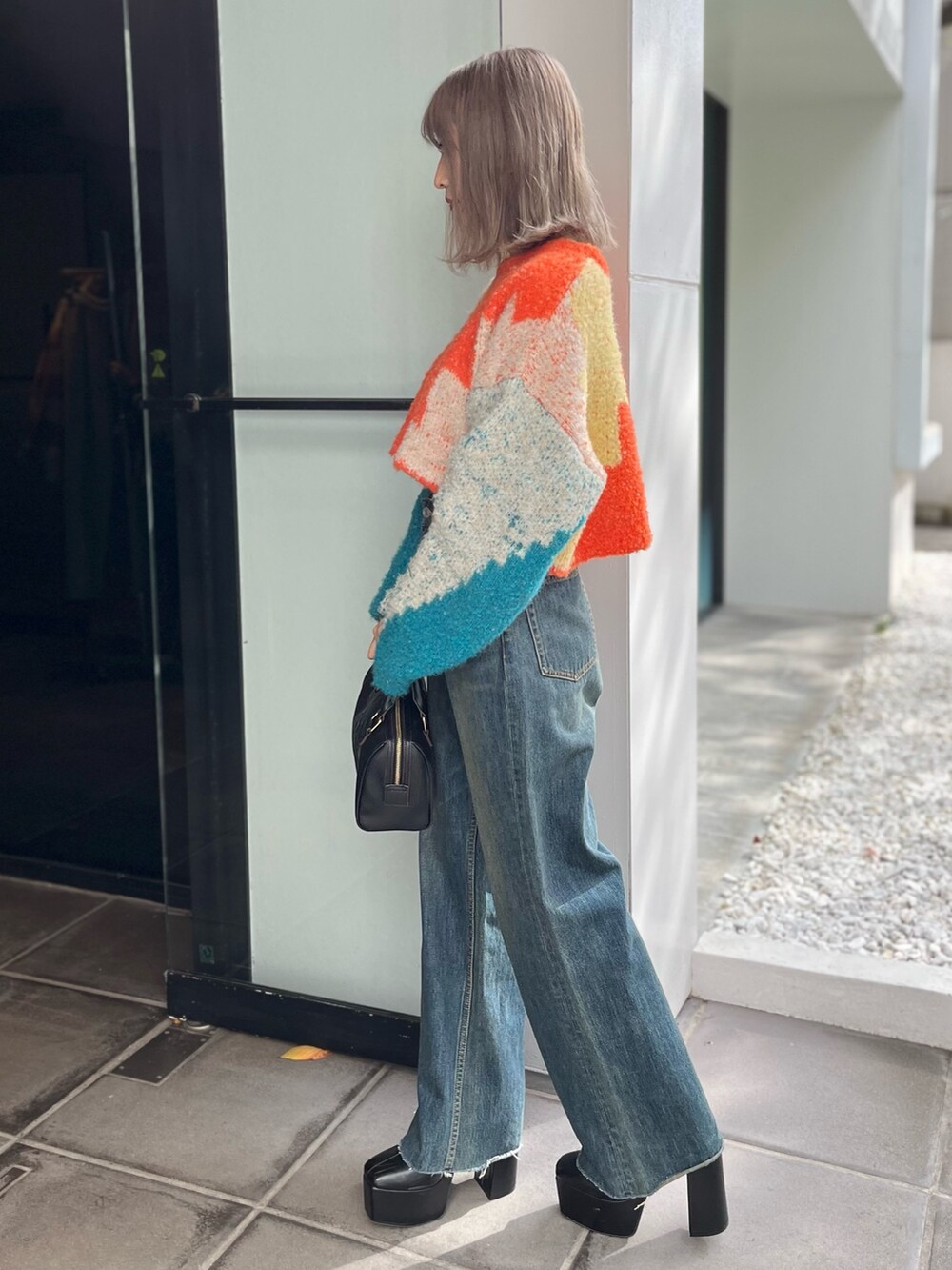 ブラック系のボストンバッグ、ブルー系のニット/セーター、ブルー系のデニムパンツを着用したレディースの冬コーディネートの2枚目の写真