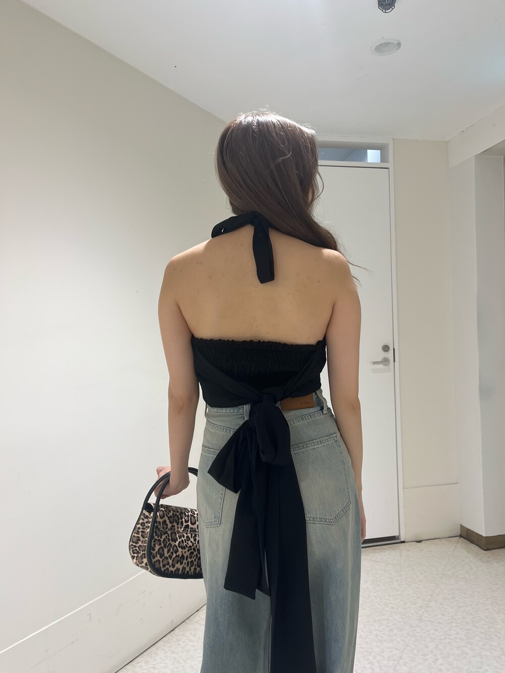 ブルー系のデニムパンツ、ブラック系のハンドバッグ、ブラック系のサンダルを着用したレディースの夏コーディネートの5枚目の写真