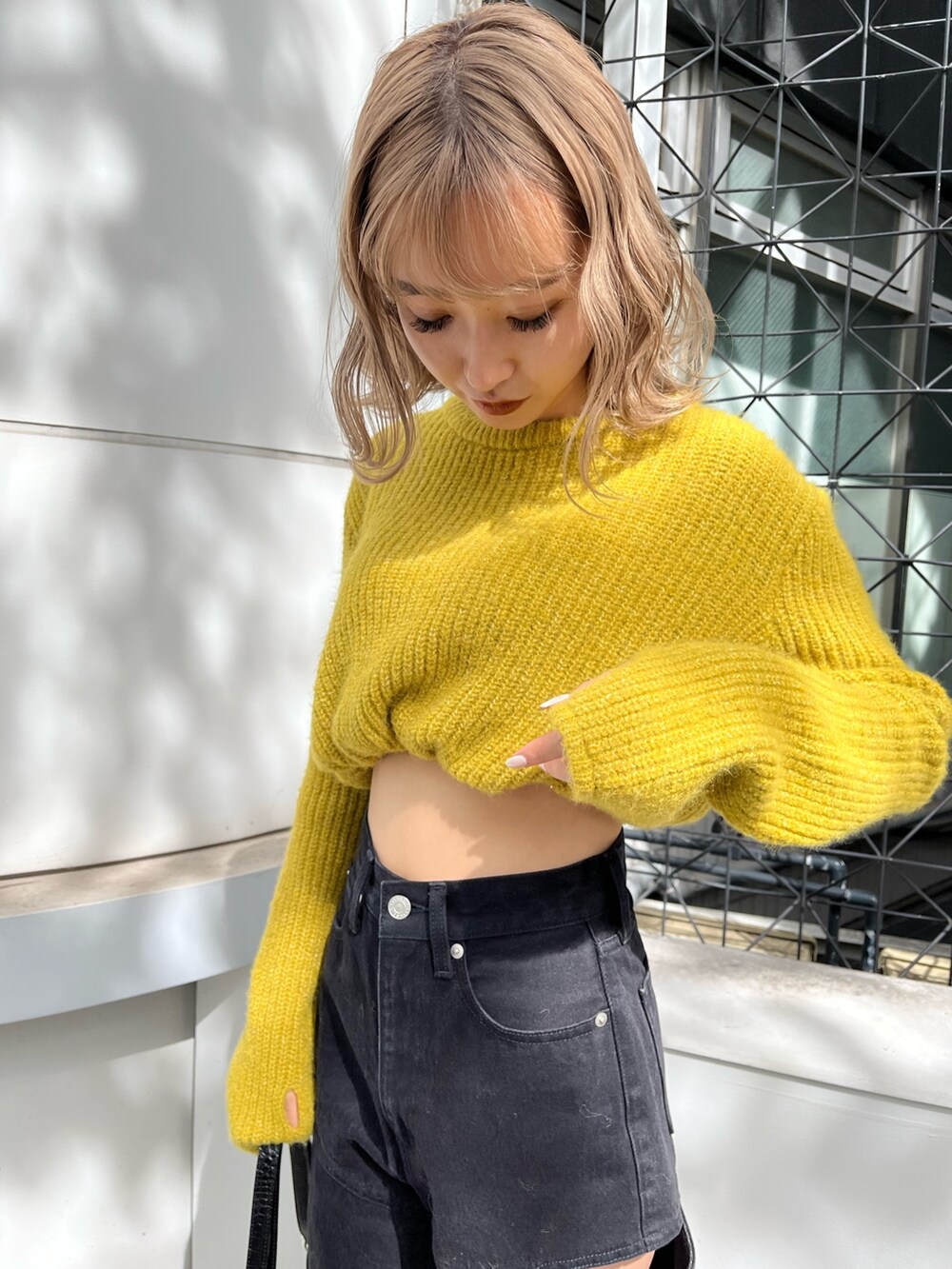 ブラック系のショルダーバッグ、ブラック系のデニムパンツ、イエロー系のニット/セーターを着用したレディースの秋コーディネートの6枚目の写真