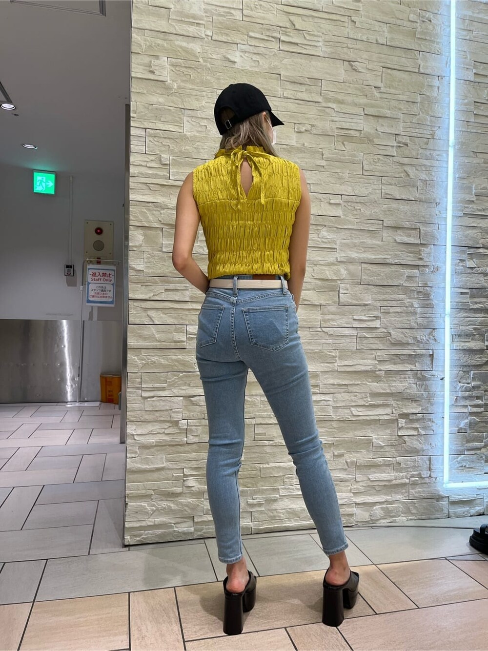 イエロー系のシャツ/ブラウス、ブラック系のサンダル、ブルー系のデニムパンツを着用したレディースの夏コーディネートの7枚目の写真