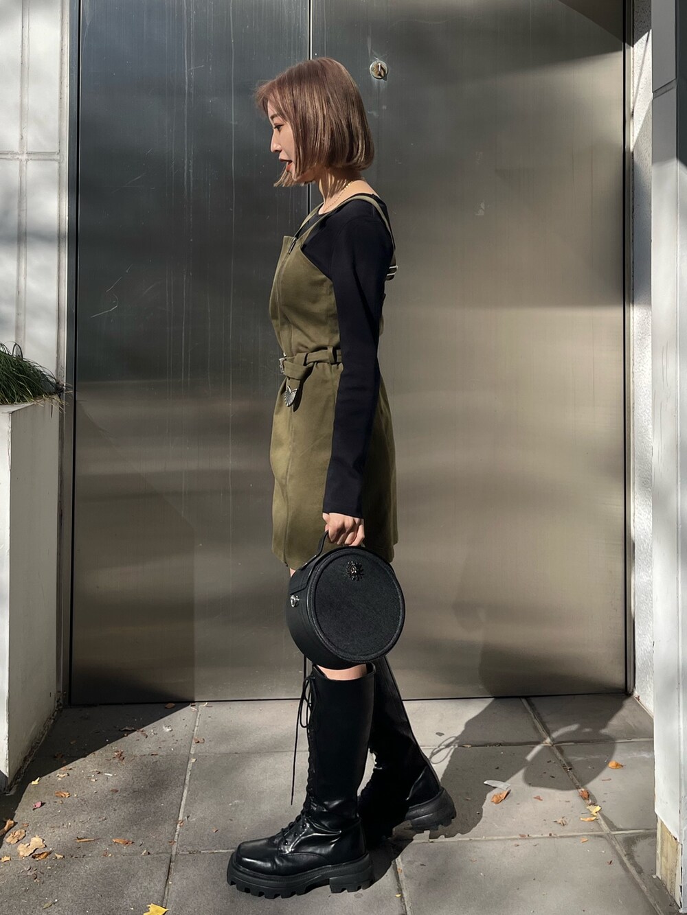 ブラック系のワンピース、ブラック系のショルダーバッグ、ブラック系のブーツを着用したレディースの冬コーディネートの2枚目の写真