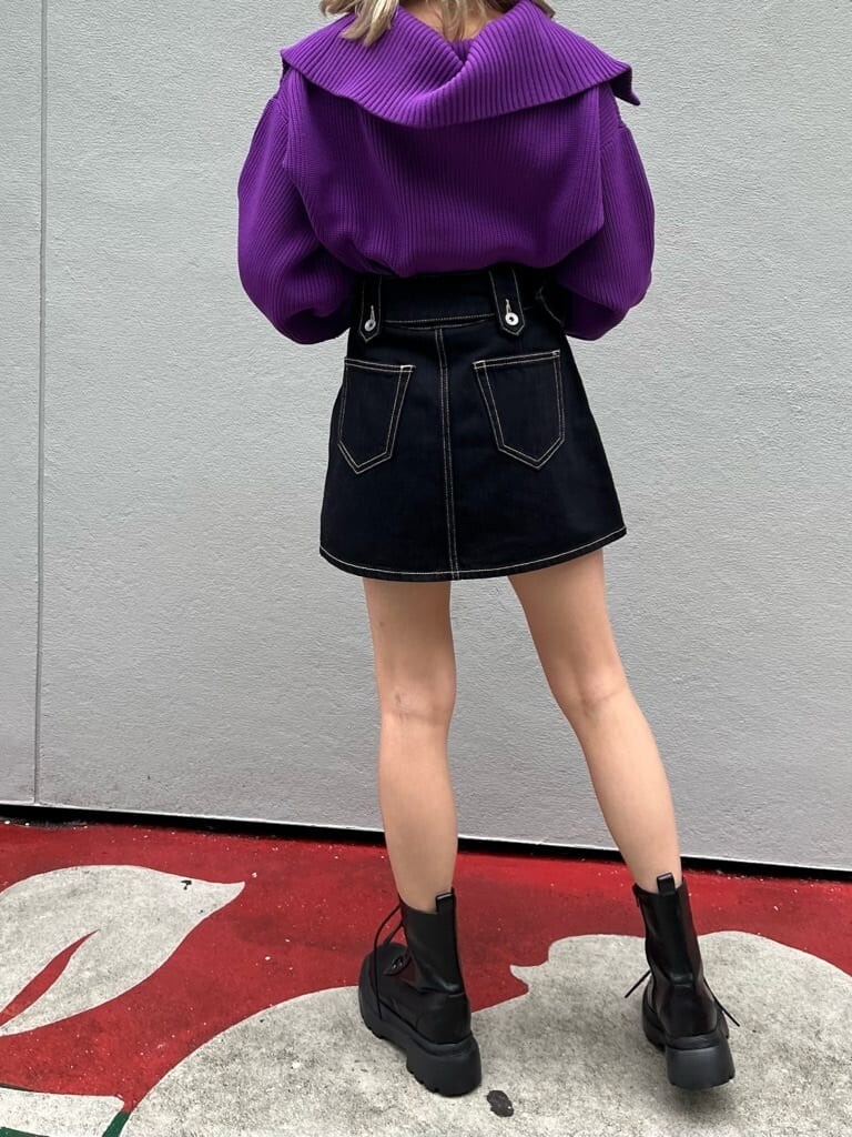 ブラック系のブーツ、ブラック系のデニムスカート、パープル系のニット/セーターを着用したレディースの秋コーディネートの4枚目の写真