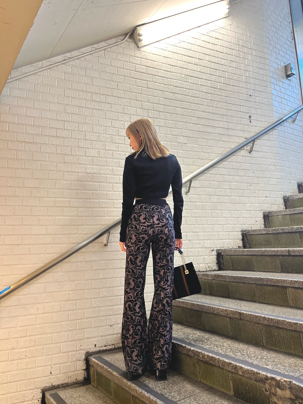 ホワイト系のその他アウター、ブラック系のその他パンツ、ブラック系のショルダーバッグを着用したレディースの冬コーディネートの8枚目の写真