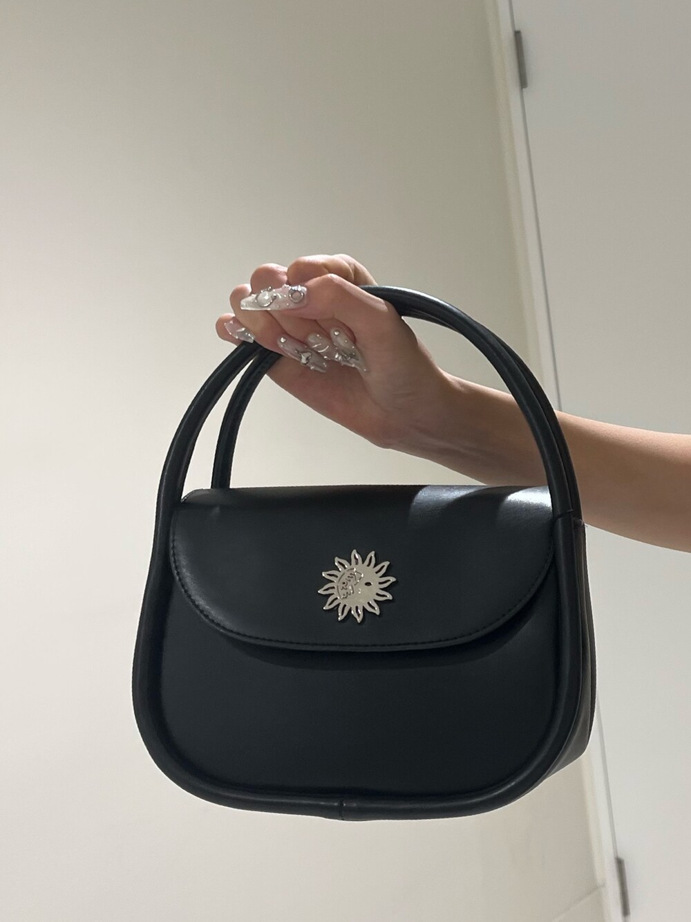 ブラック系のハンドバッグ、ブルー系のデニムパンツ、ブルー系のニット/セーターを着用したレディースの夏コーディネートの7枚目の写真