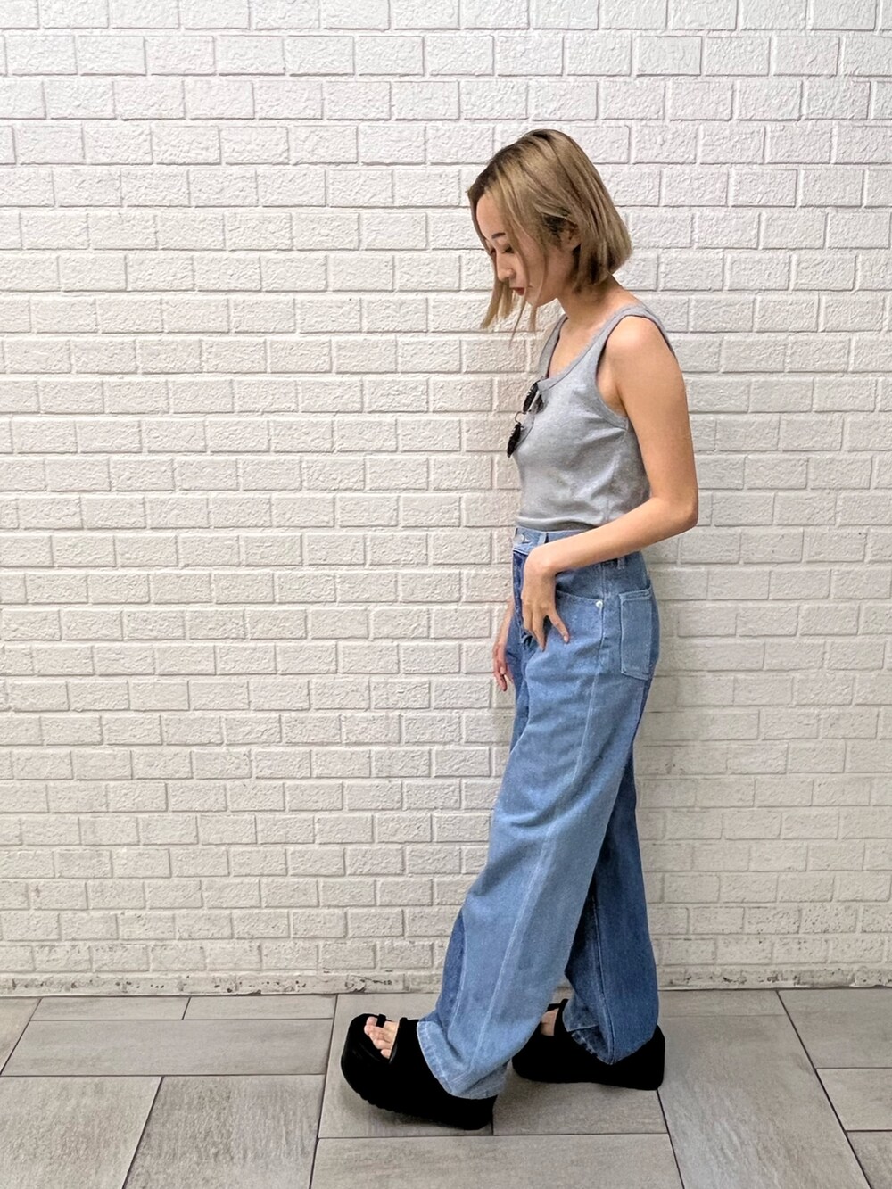 ブルー系のデニムパンツ、ブラック系のサンダル、グレー系のタンクトップを着用したレディースの夏コーディネートの2枚目の写真