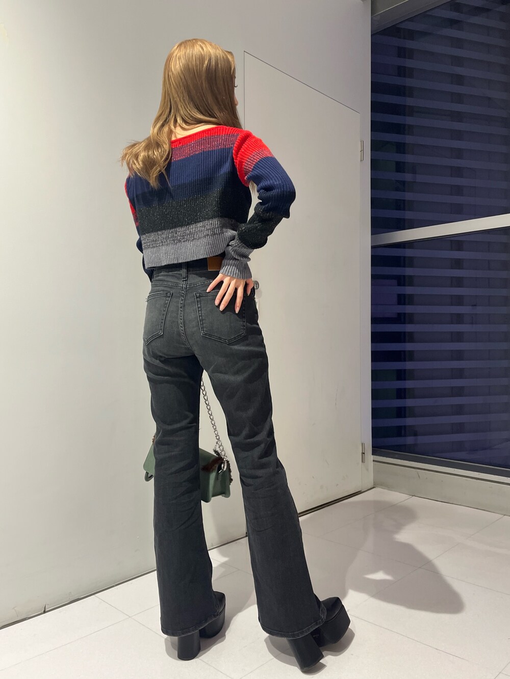 レッド系のニット/セーター、ブラック系のデニムパンツ、ブルー系のショルダーバッグを着用したレディースの秋コーディネートの3枚目の写真