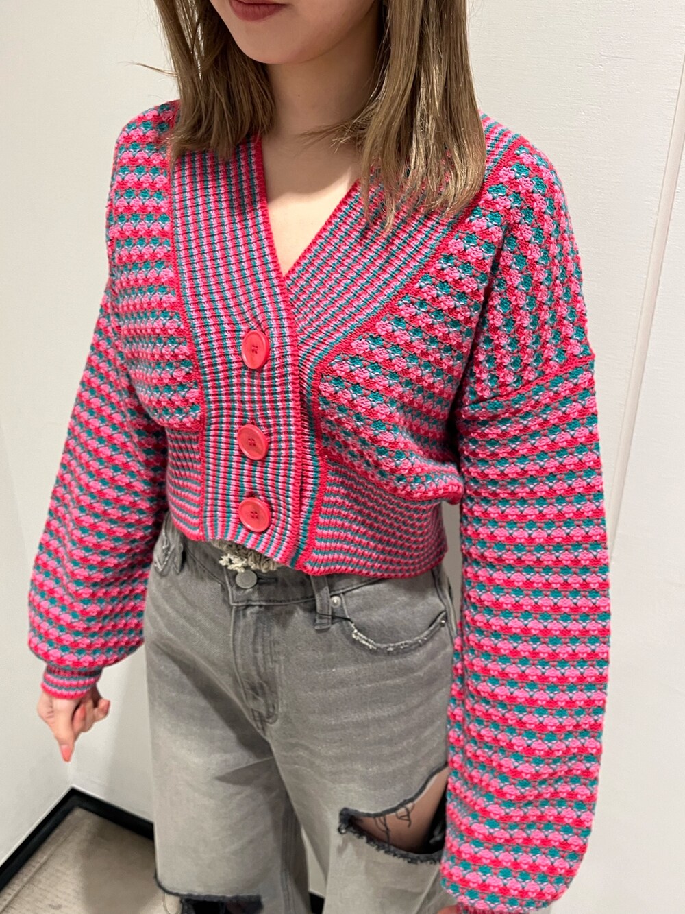 ブラック系のデニムパンツ、ピンク系のカーディガン/ボレロ、ブラック系のブーツを着用したレディースの冬コーディネートの5枚目の写真