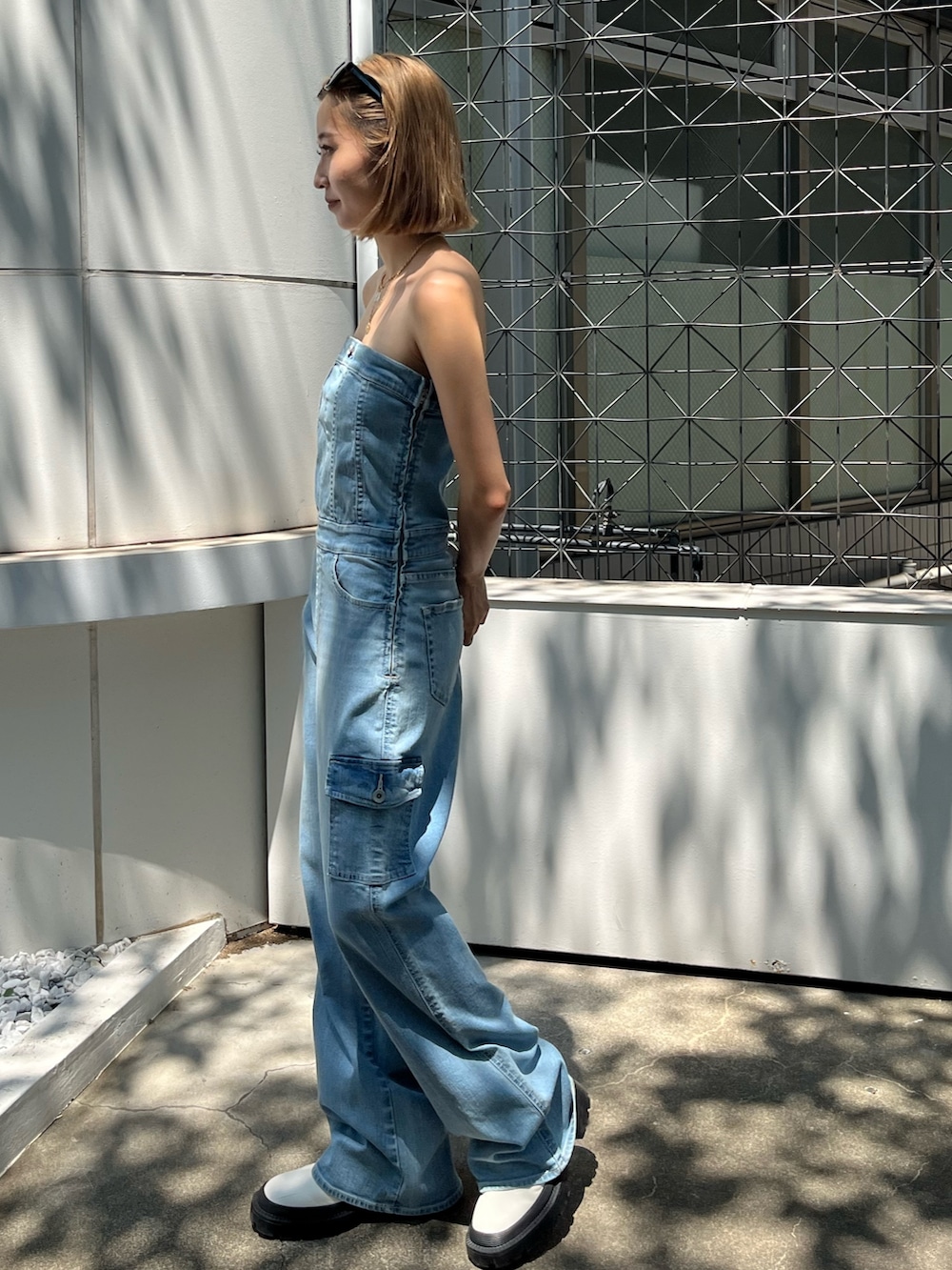 ブルー系のつなぎ/オールインワン、ホワイト系のブーツ、ブラック系のサングラスを着用したレディースの夏コーディネートの2枚目の写真
