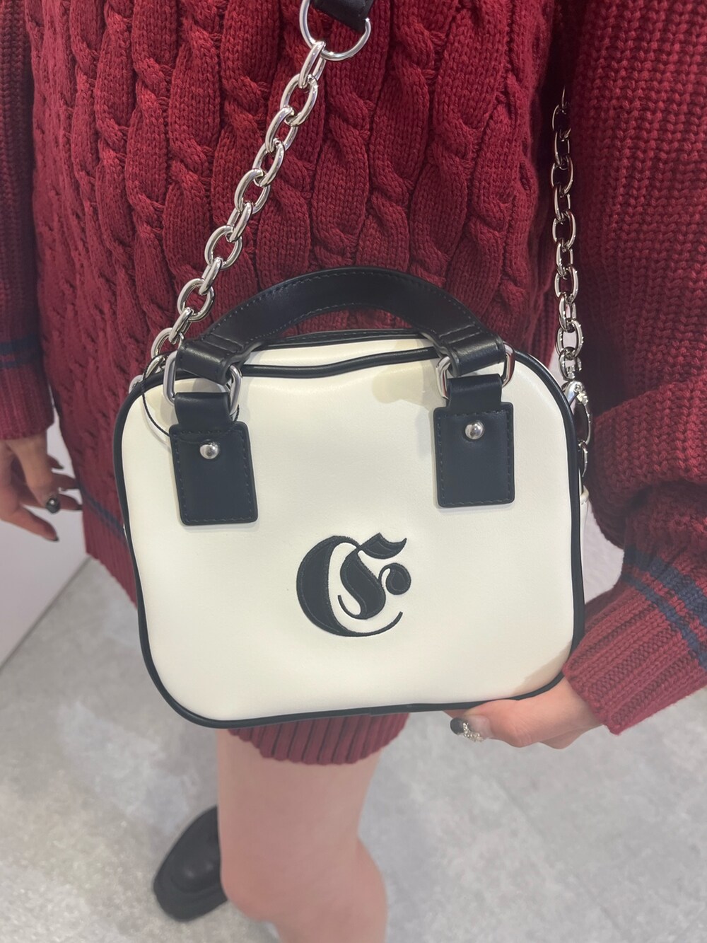 レッド系のニット/セーター、シルバー系のブーツ、ホワイト系のショルダーバッグを着用したレディースの夏コーディネートの4枚目の写真