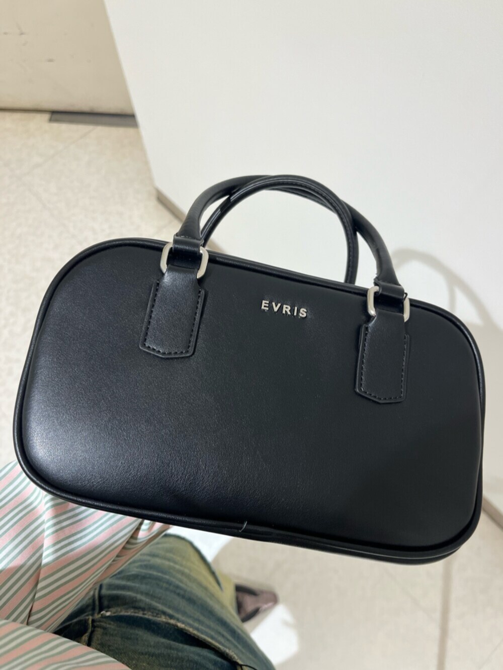 ブラック系のブーツ、ブラック系のボストンバッグ、ブラック系のスカートを着用したレディースの春コーディネートの7枚目の写真