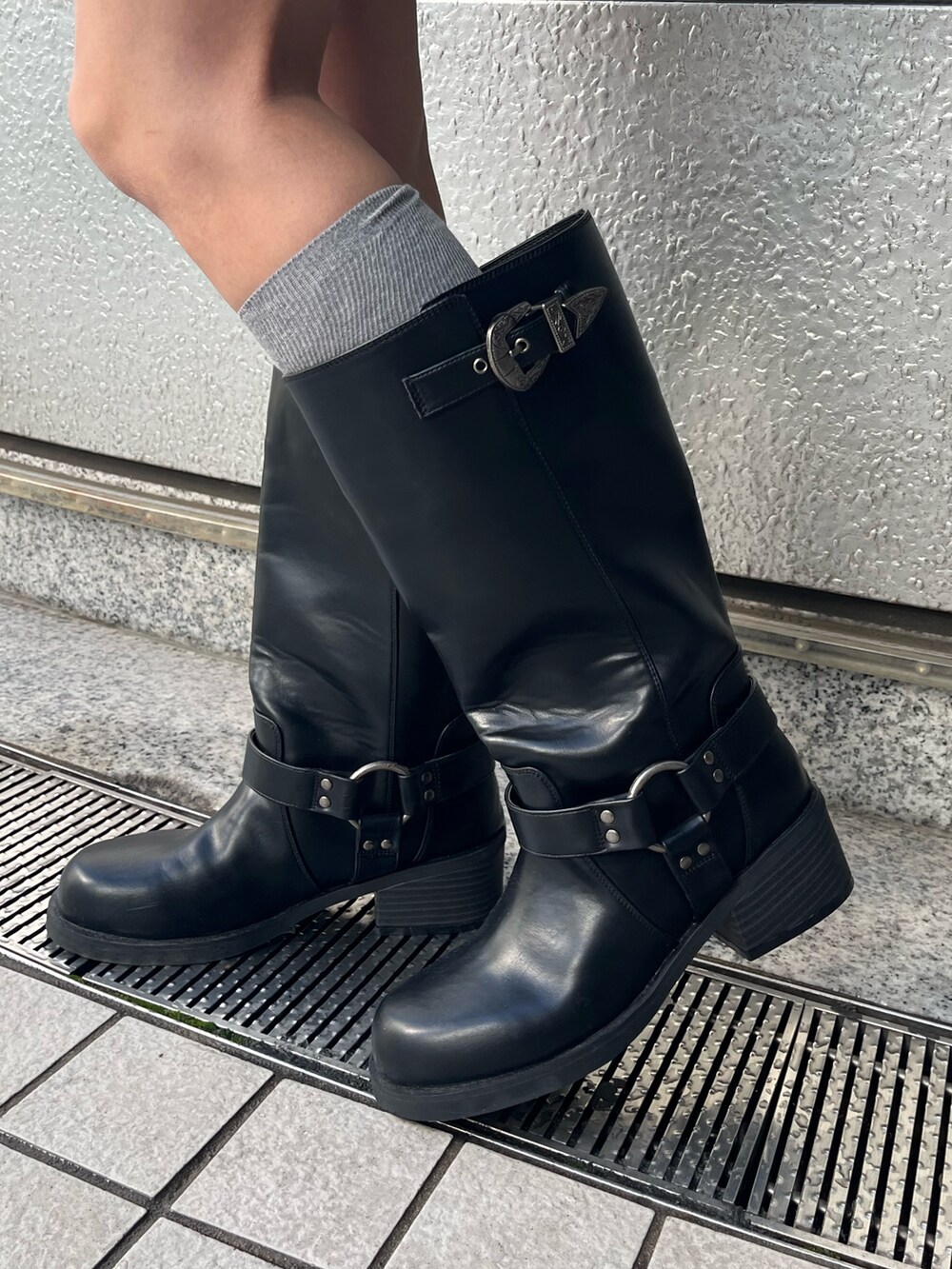 グレー系のハンドバッグ、ブラック系のブーツ、ホワイト系のニット/セーターを着用したレディースの冬コーディネートの4枚目の写真