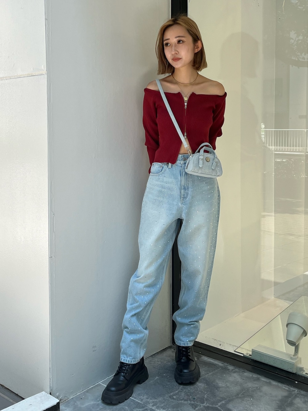 ブルー系のデニムパンツ、レッド系のニット/セーター、ブルー系のハンドバッグを着用したレディースの秋コーディネートの2枚目の写真