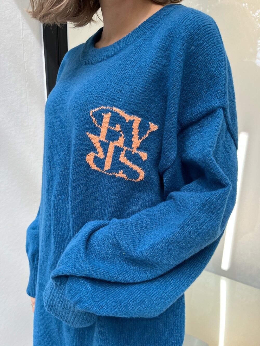 シルバー系のショルダーバッグ、ホワイト系のブーツ、ブルー系のニット/セーターを着用したレディースの秋コーディネートの6枚目の写真