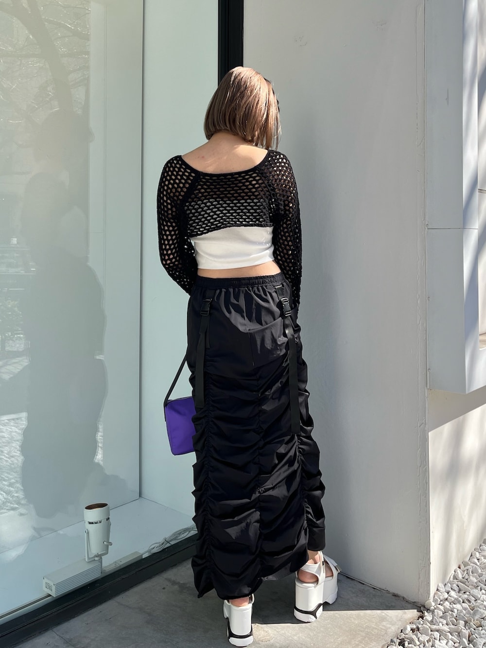 ブラック系のスカート、ブラック系のニット/セーター、パープル系のハンドバッグを着用したレディースの春コーディネートの2枚目の写真