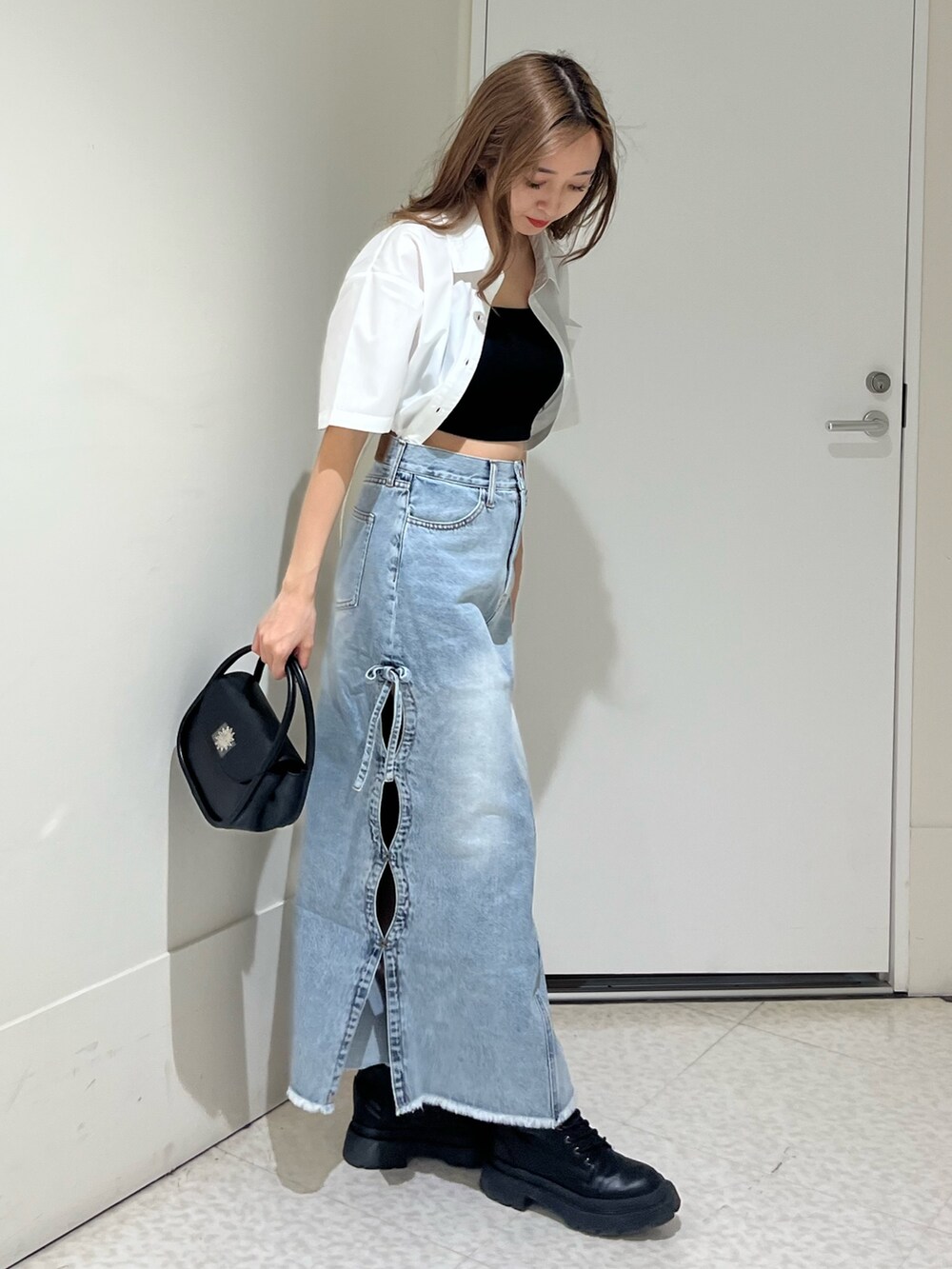 ブラック系のブーツ、ブルー系のデニムスカート、ブラック系のハンドバッグを着用したレディースの春コーディネートの4枚目の写真