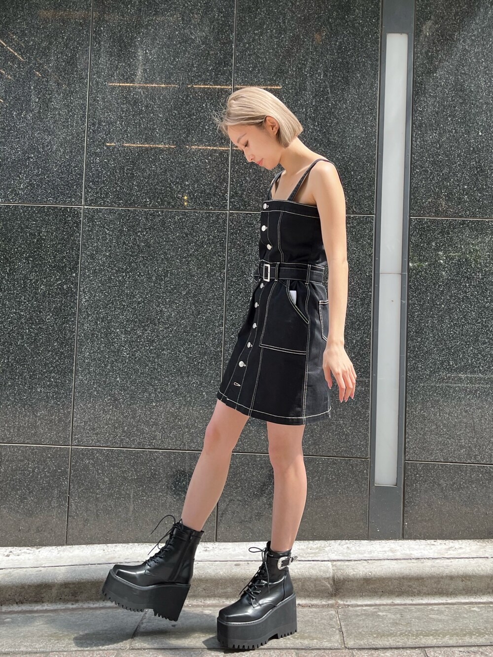 ブラック系のブーツ、ブラック系のジャンパースカートを着用したレディースの春コーディネートの2枚目の写真