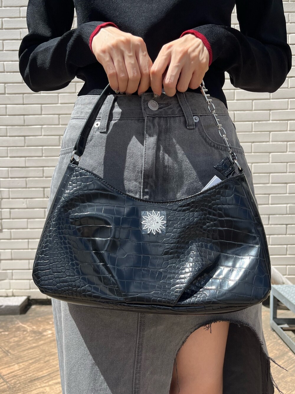 ブラック系のデニムスカート、ブラック系のブーツ、ブラック系のハンドバッグを着用したレディースの夏コーディネートの7枚目の写真