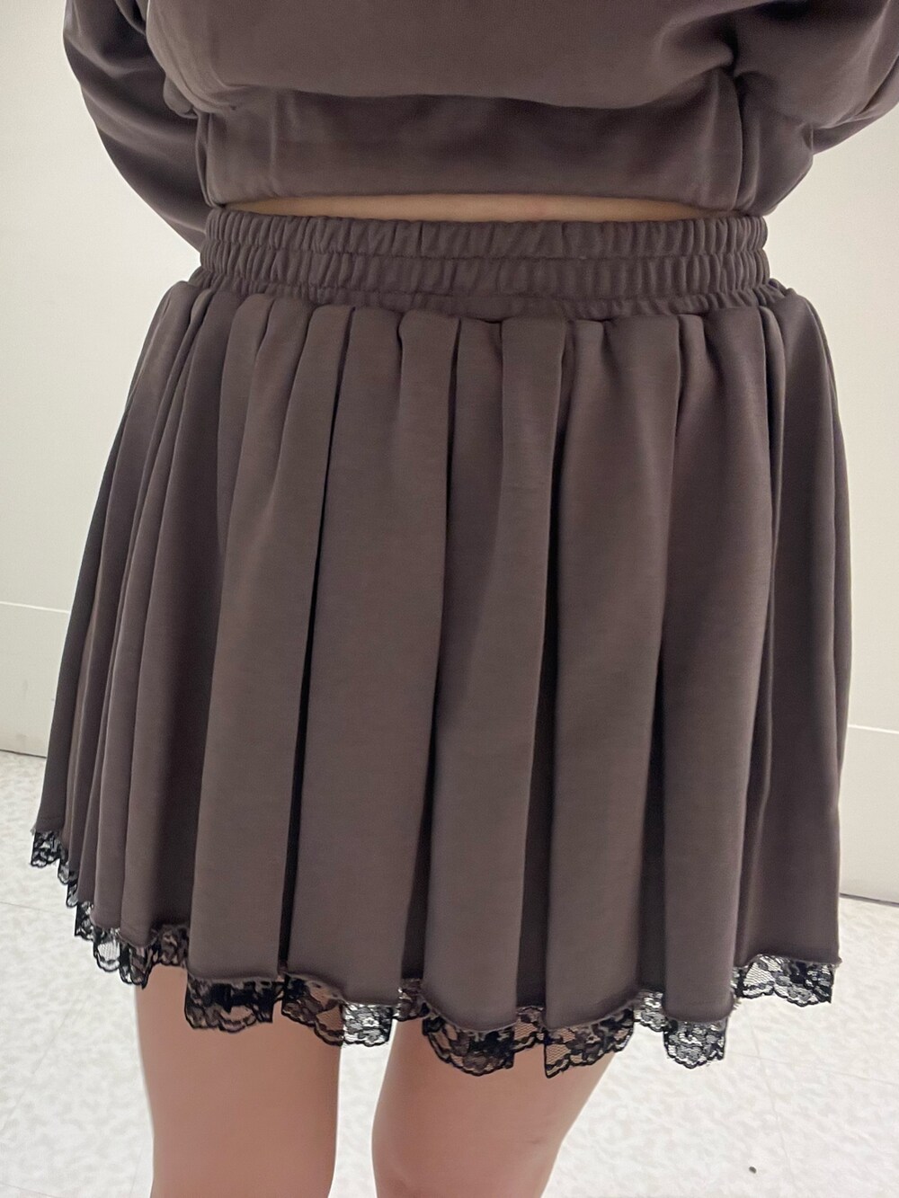 ブラック系のスウェット、ブラック系のスカート、ブラウン系のハンドバッグを着用したレディースの春コーディネートの6枚目の写真