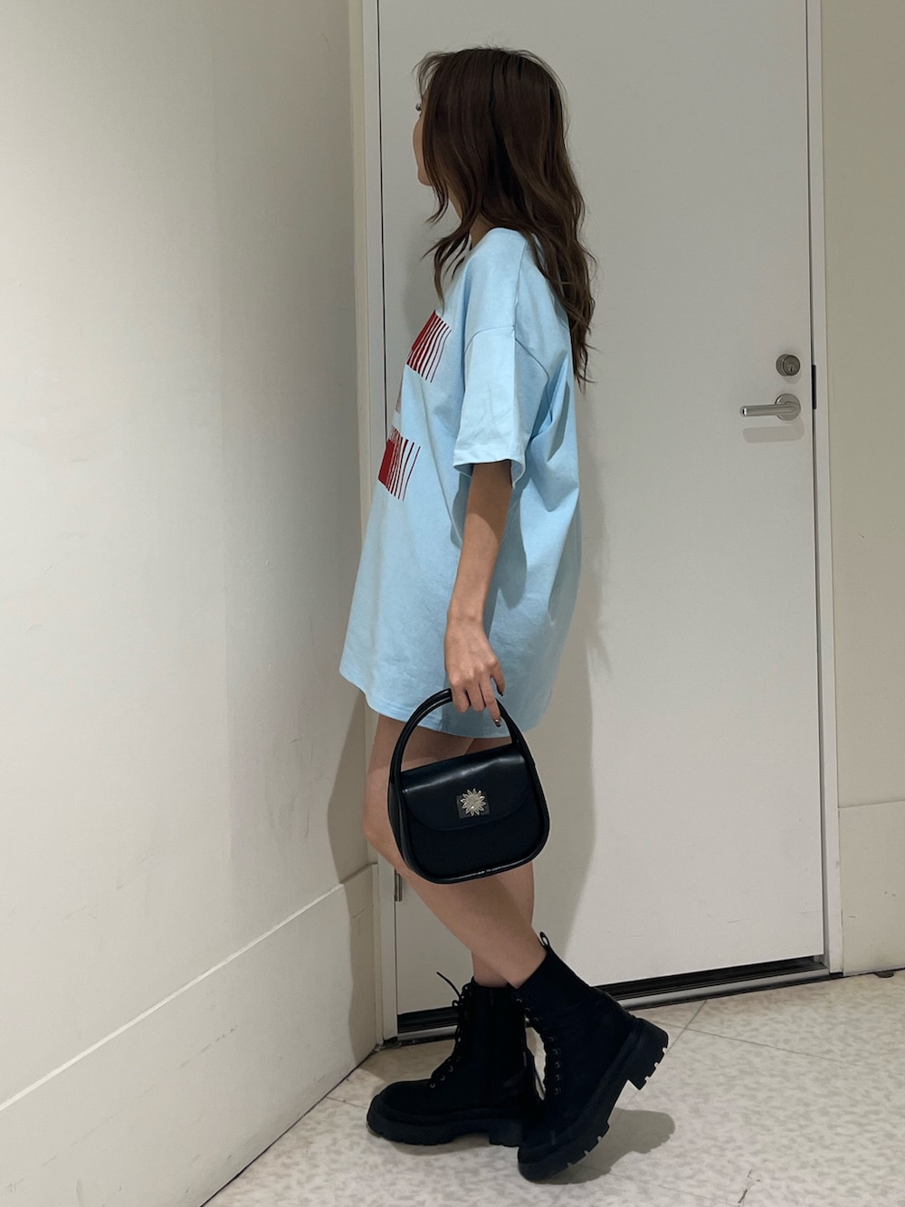 ブラック系のハンドバッグ、ブラック系のブーツ、ブルー系のTシャツ/カットソーを着用したレディースの春コーディネートの2枚目の写真