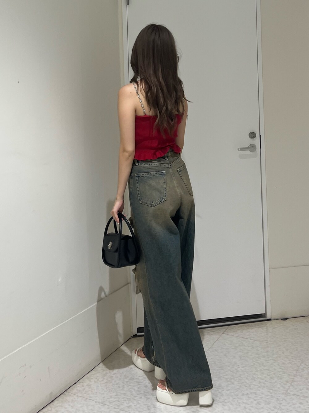 ブルー系のデニムパンツ、ブラック系のハンドバッグ、ブラック系のサンダルを着用したレディースの夏コーディネートの2枚目の写真