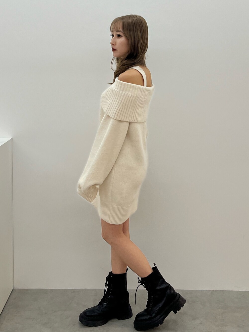 グレー系のハンドバッグ、ホワイト系のワンピース、ブラック系のブーツを着用したレディースの冬コーディネートの2枚目の写真