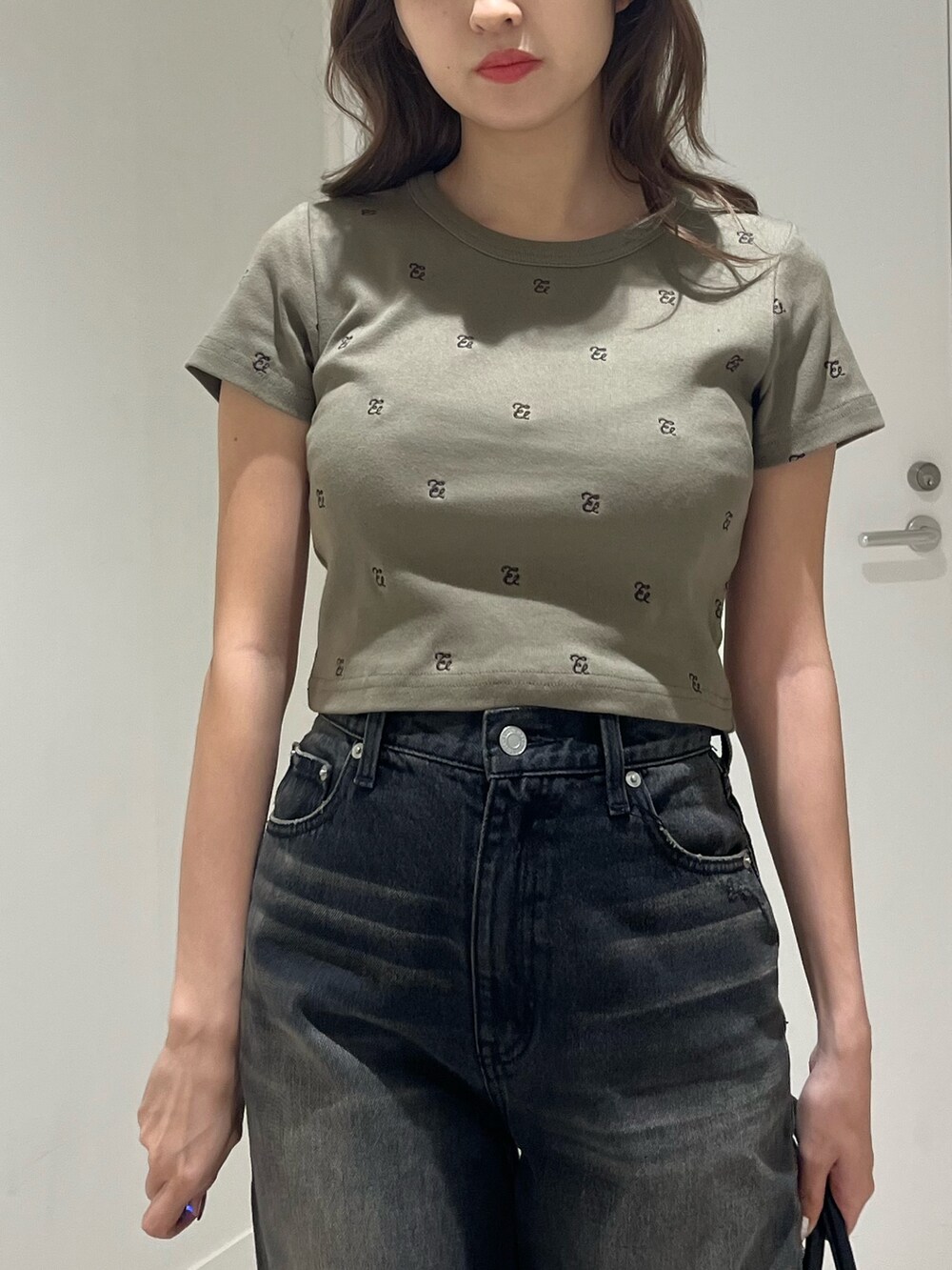 グリーン系のTシャツ/カットソー、ブラック系のブーツ、ブラック系のハンドバッグを着用したレディースの春コーディネートの5枚目の写真