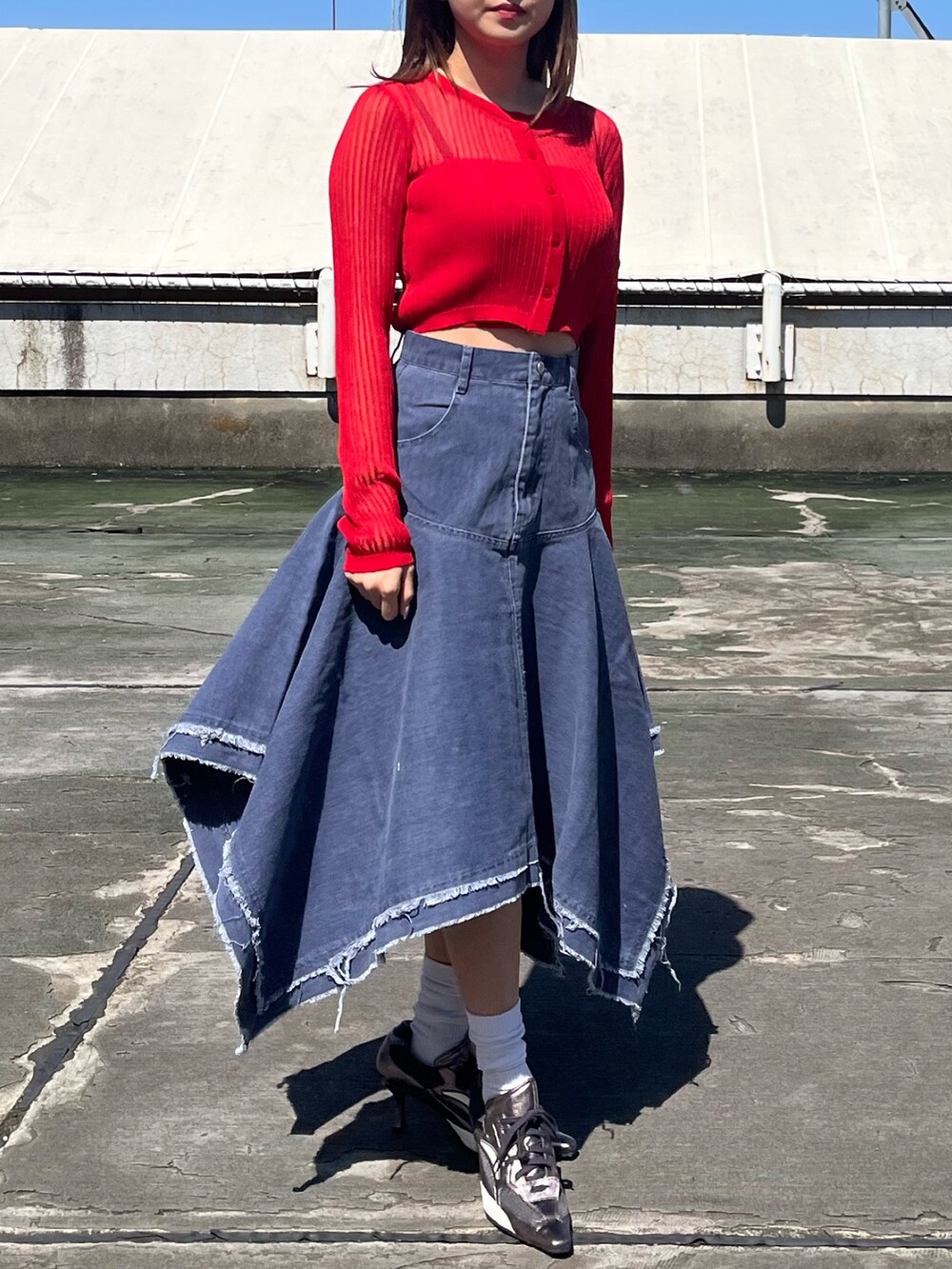レッド系のニット/セーター、シルバー系のパンプス、ブルー系のデニムスカートを着用したレディースの春コーディネートの5枚目の写真