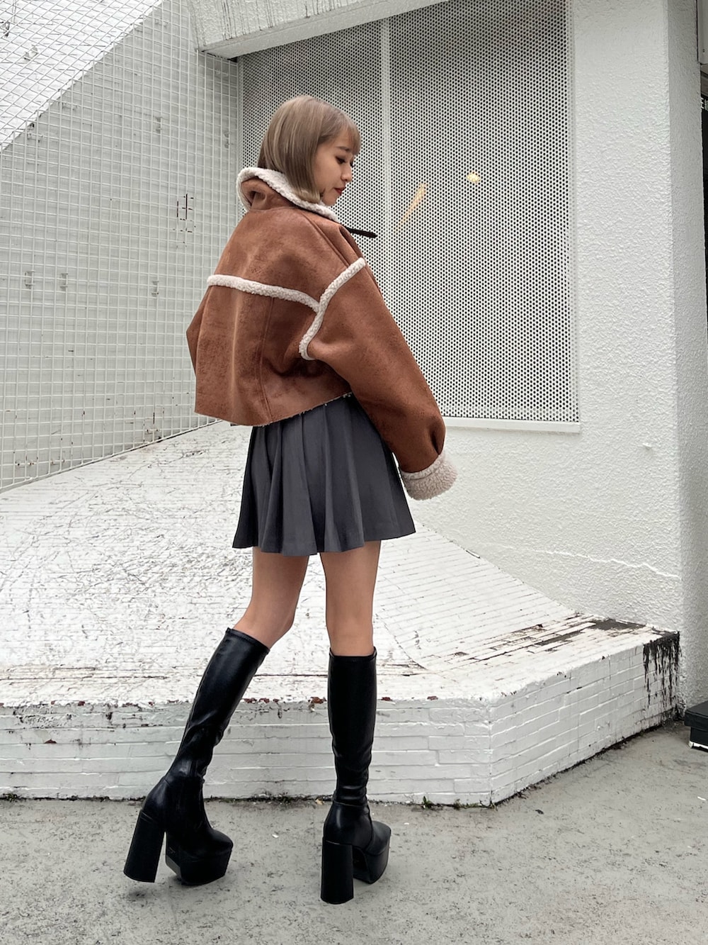 グレー系のスカート、グレー系のTシャツ/カットソー、ブラック系のムートンコートを着用したレディースの秋コーディネートの5枚目の写真