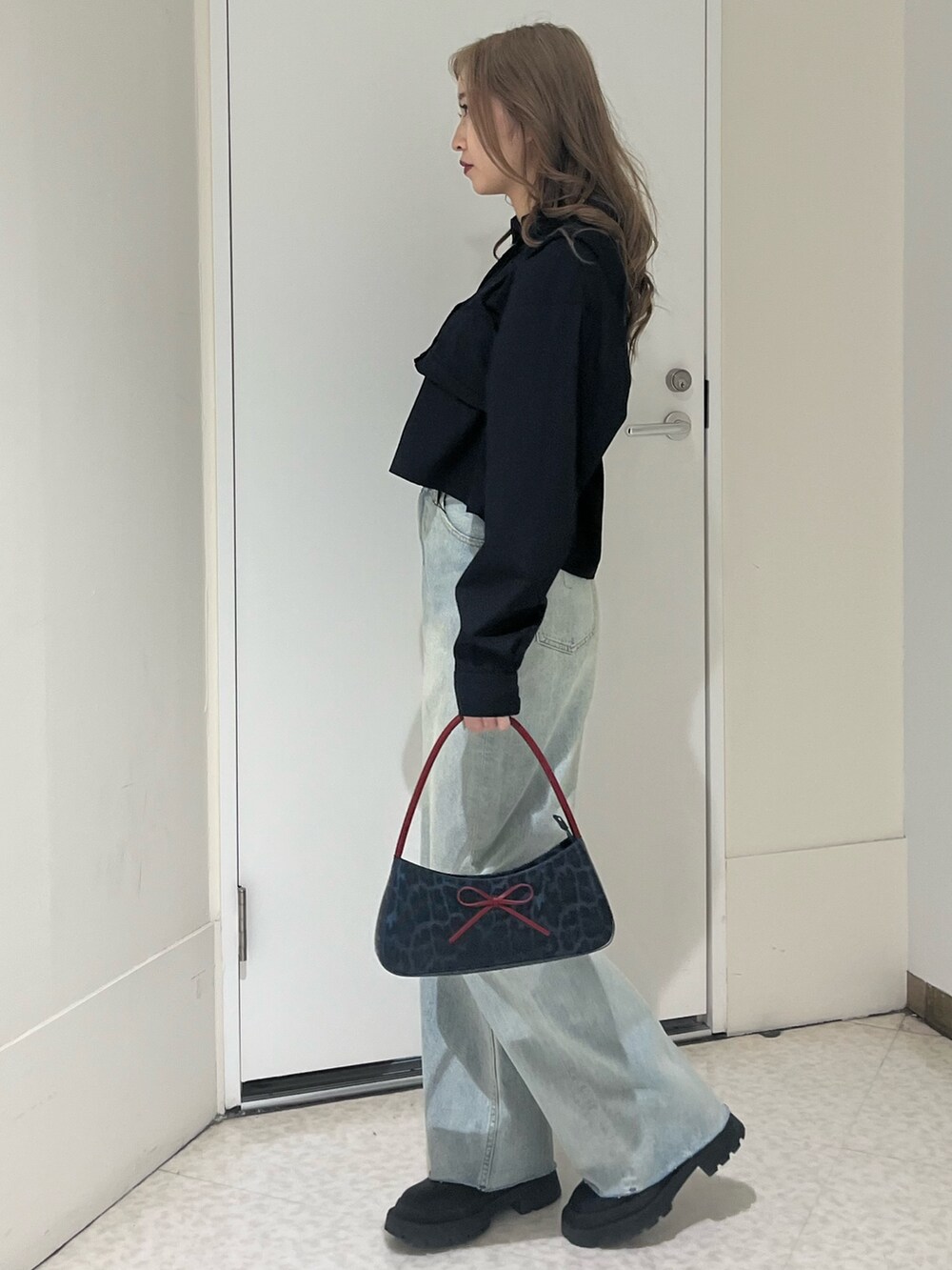 ブラック系のシャツ/ブラウス、ブルー系のデニムパンツ、ブラウン系のハンドバッグを着用したレディースの春コーディネートの2枚目の写真