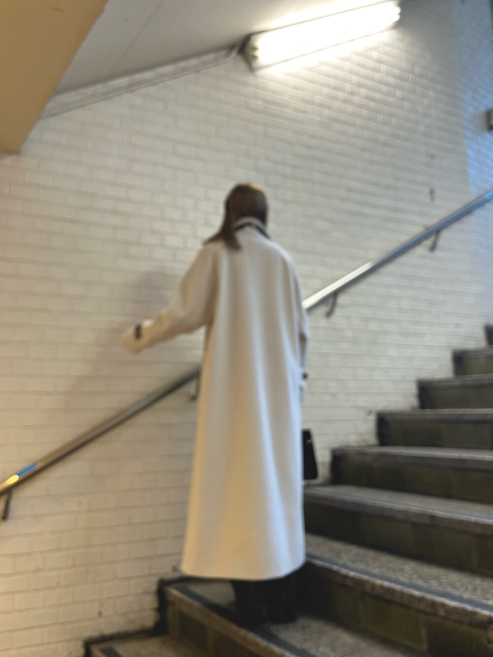 ホワイト系のその他アウター、ブラック系のその他パンツ、ブラック系のショルダーバッグを着用したレディースの冬コーディネートの2枚目の写真