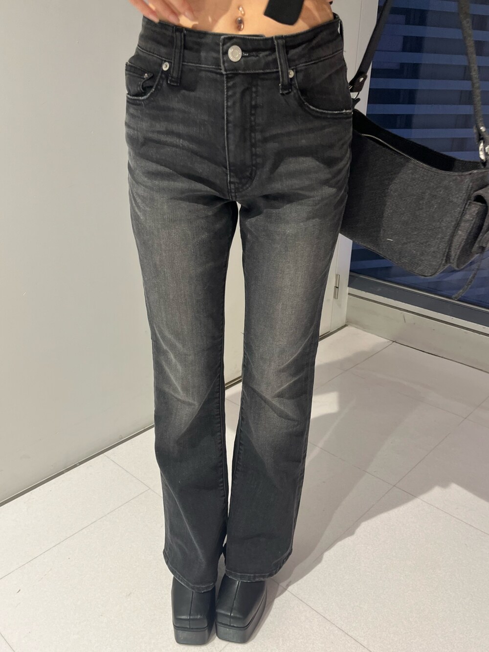 ブラック系のデニムパンツ、ブラック系のハンドバッグ、ブラック系のブーツを着用したレディースの秋コーディネートの4枚目の写真