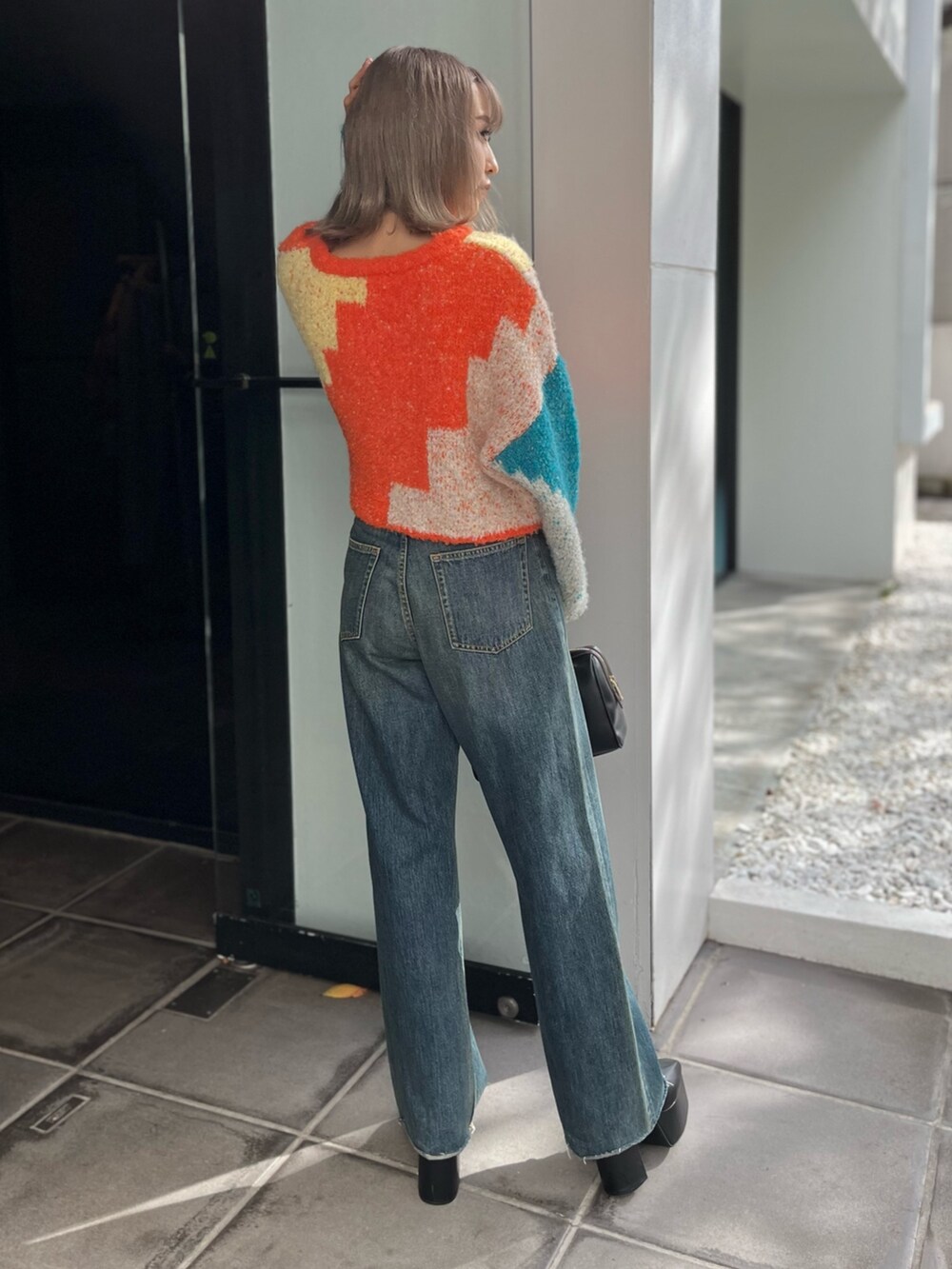 ブラック系のボストンバッグ、ブルー系のニット/セーター、ブルー系のデニムパンツを着用したレディースの冬コーディネートの4枚目の写真