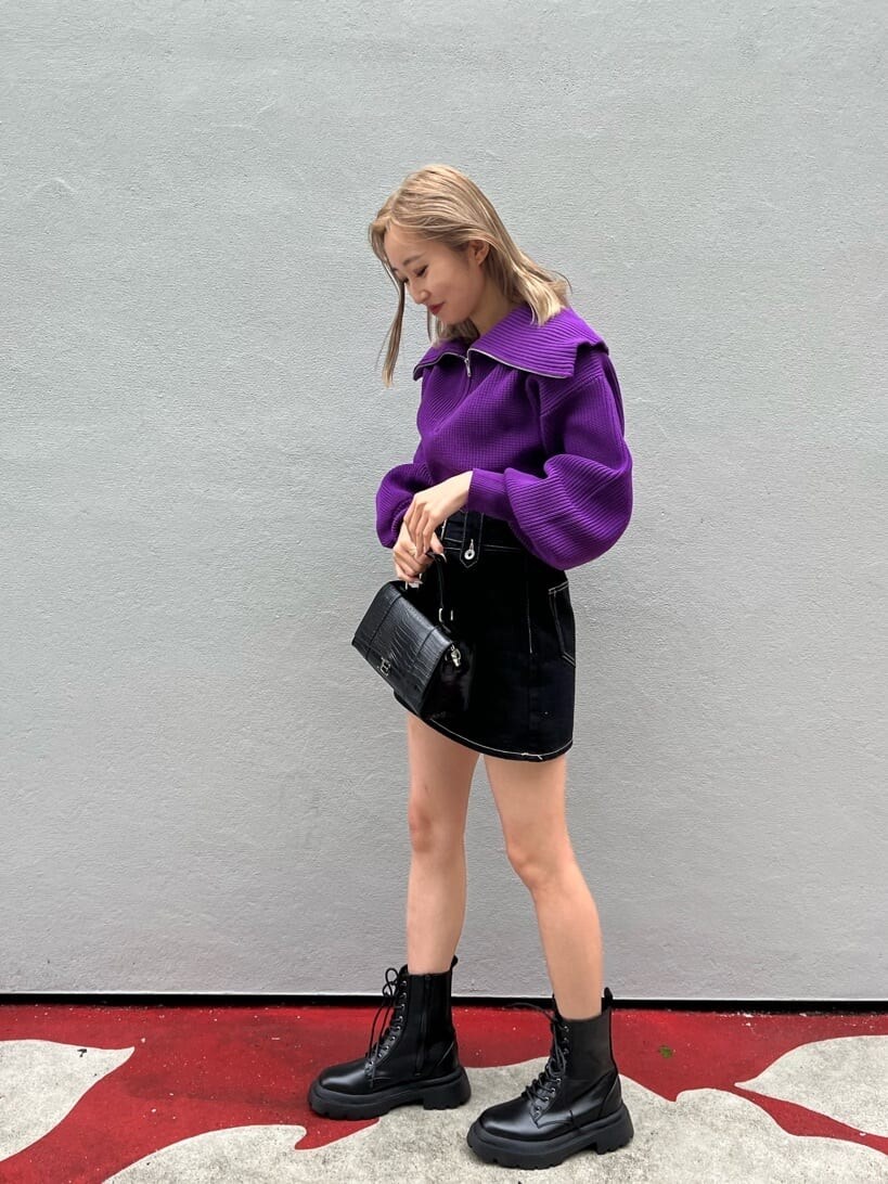 ブラック系のブーツ、ブラック系のデニムスカート、パープル系のニット/セーターを着用したレディースの秋コーディネートの3枚目の写真