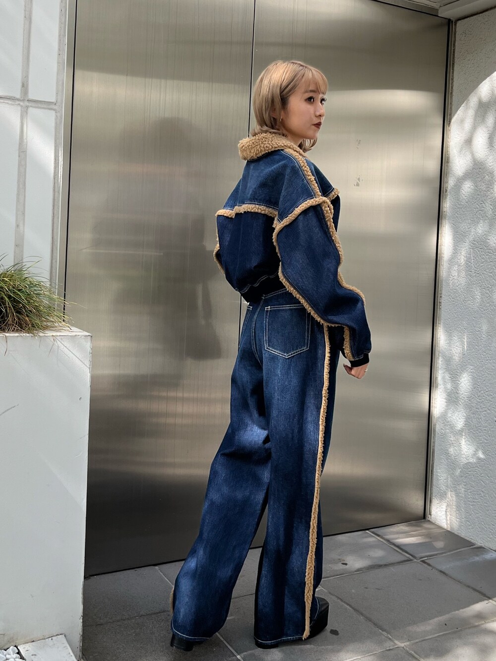 ブラック系のショルダーバッグ、ブラック系のブーツ、ブルー系のデニムパンツを着用したレディースの秋コーディネートの6枚目の写真