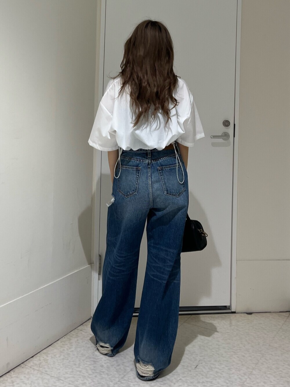 ブラック系のブーツ、ブルー系のデニムパンツ、その他のショルダーバッグを着用したレディースの春コーディネートの3枚目の写真