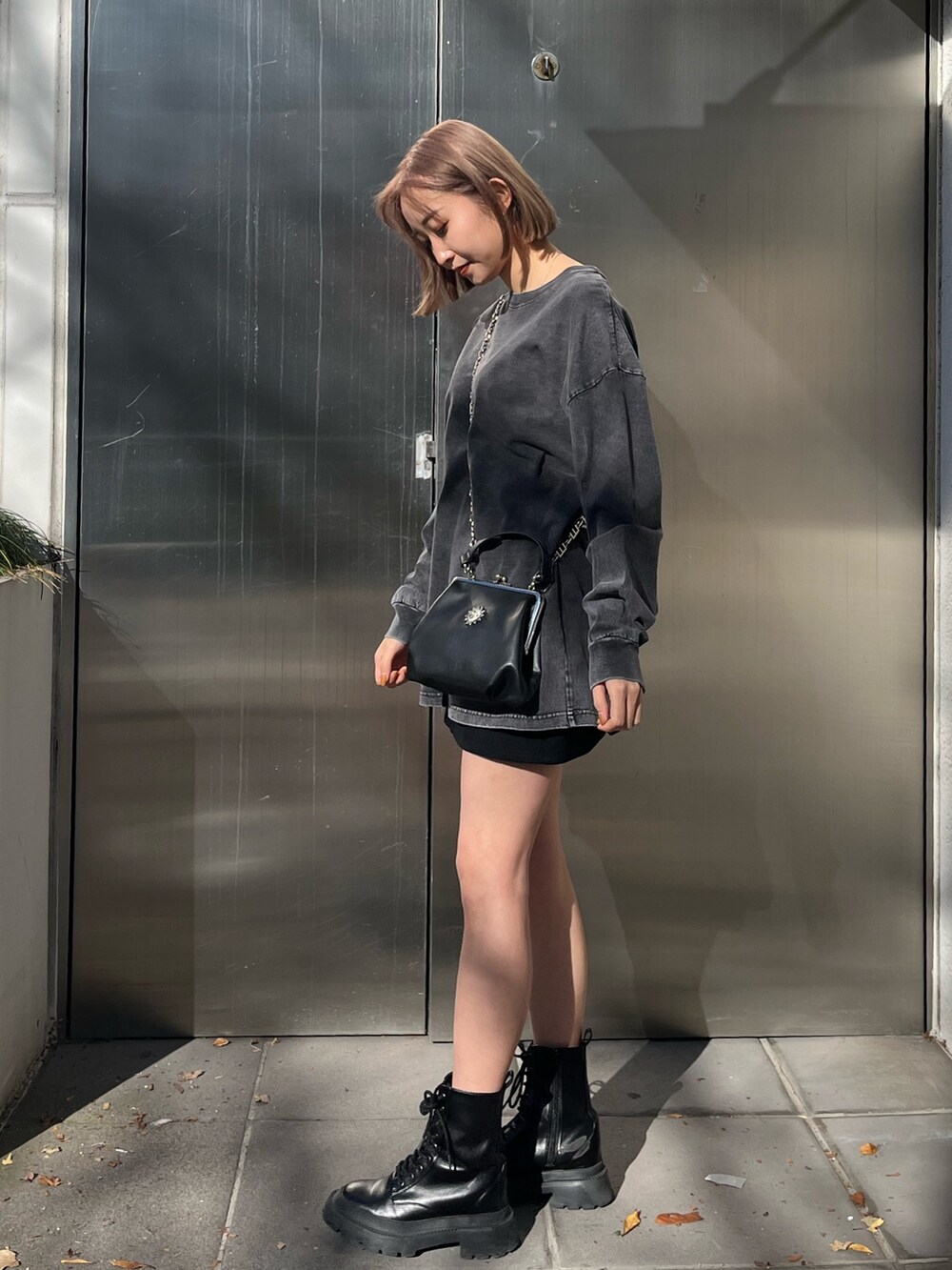 グレー系のTシャツ/カットソー、ブラック系のショルダーバッグ、ブラック系のブーツを着用したレディースの冬コーディネートの2枚目の写真