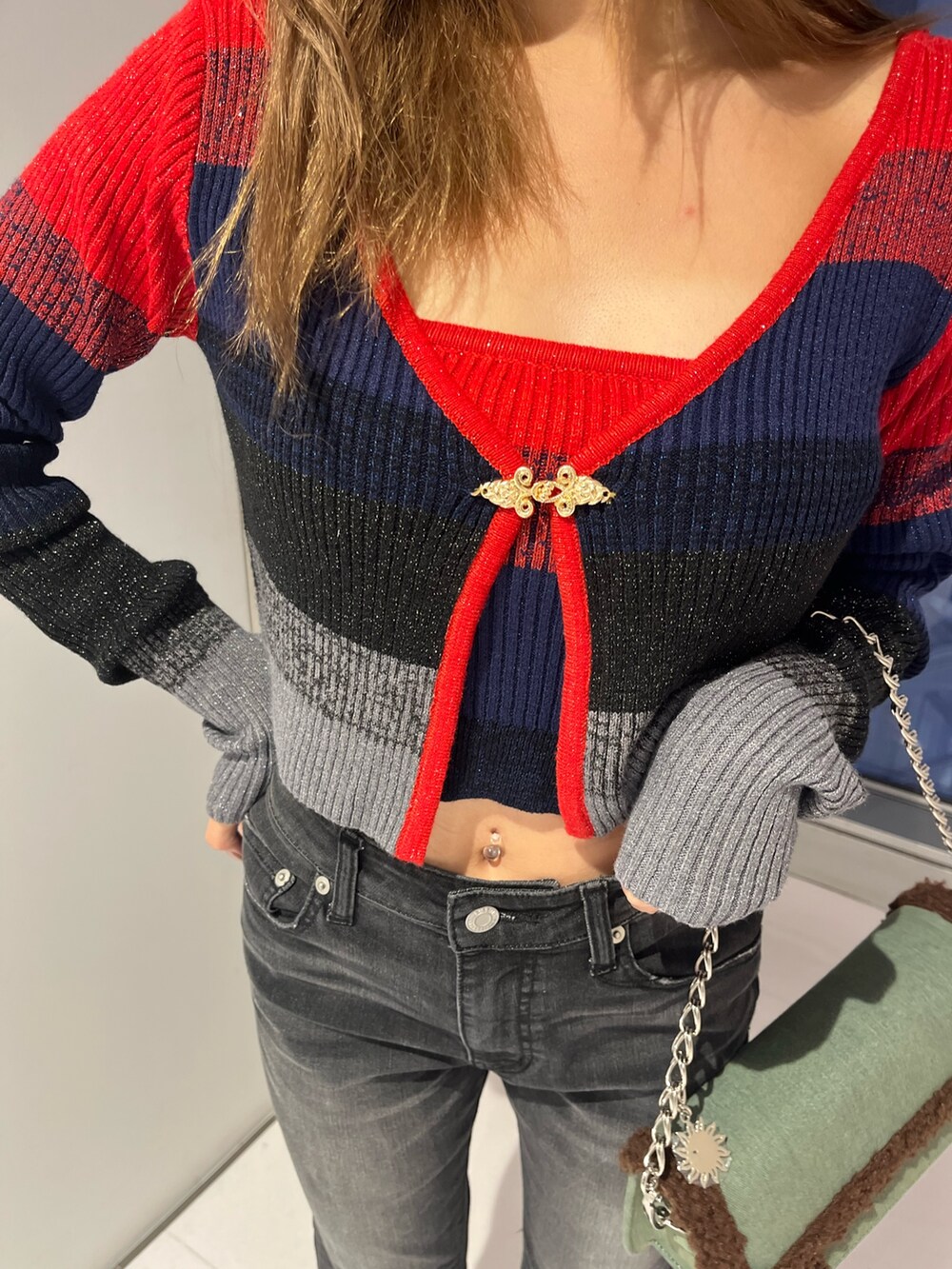 レッド系のニット/セーター、ブラック系のデニムパンツ、ブルー系のショルダーバッグを着用したレディースの秋コーディネートの4枚目の写真