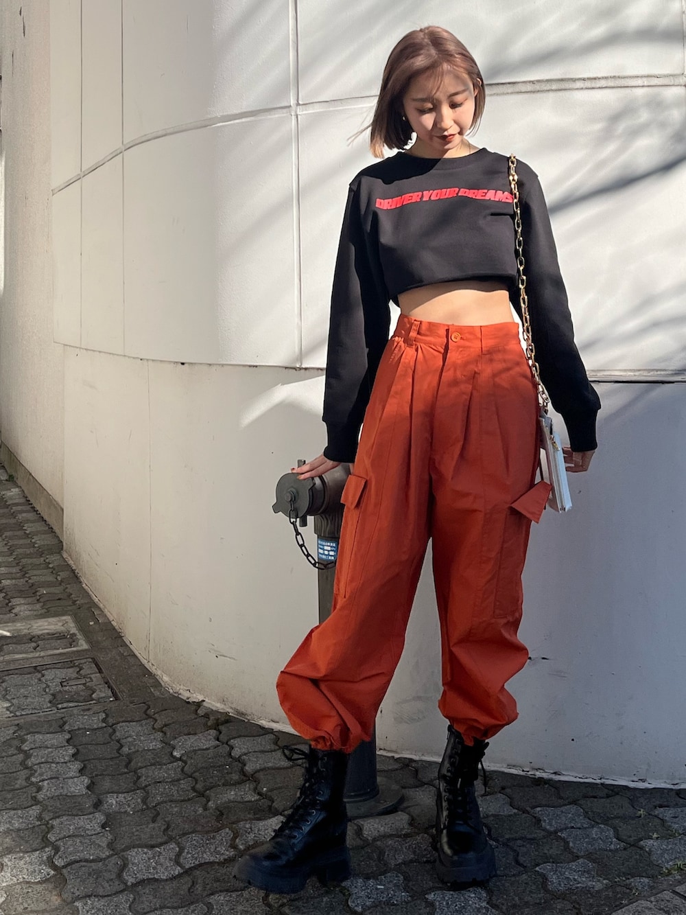 オレンジ系のカーゴパンツ、ホワイト系のブーツ、ブラック系のTシャツ/カットソーを着用したレディースの冬コーディネートの2枚目の写真