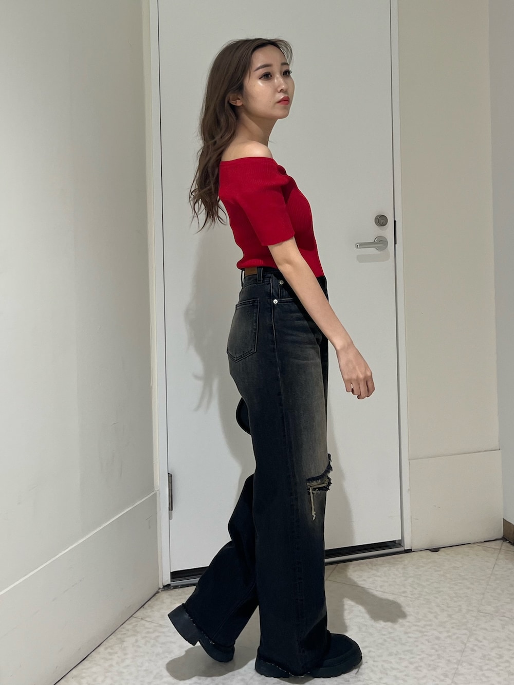 ブラック系のブーツ、ブラック系のデニムパンツ、ブラック系のハンドバッグを着用したレディースの春コーディネートの4枚目の写真