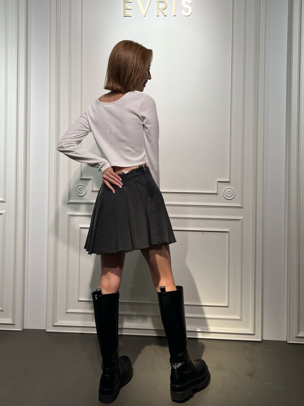 ブラック系のブーツ、ブラック系のデニムスカート、ホワイト系のTシャツ/カットソーを着用したレディースの夏コーディネートの6枚目の写真