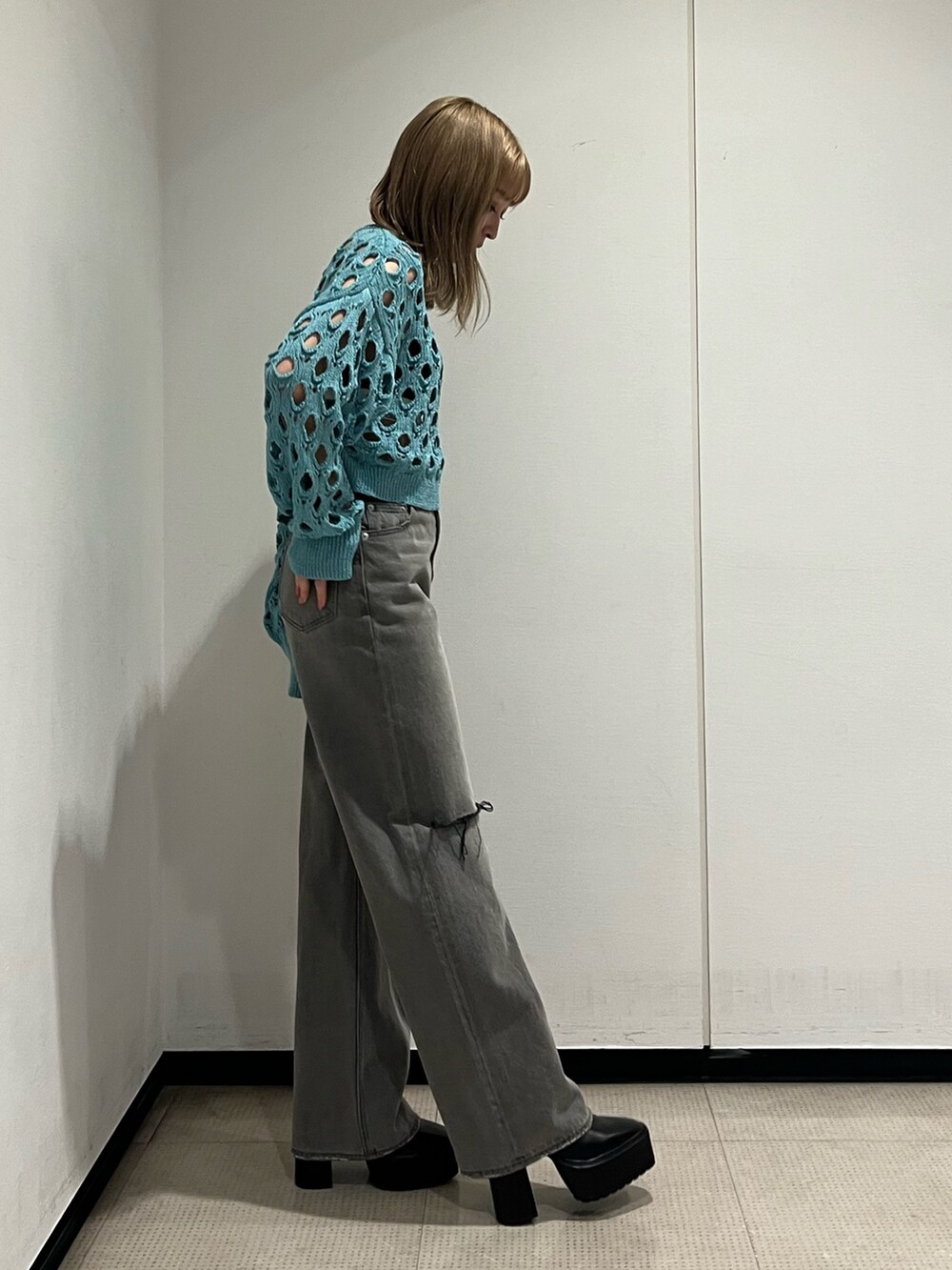 ブラック系のデニムパンツ、ブラック系のブーツ、ブルー系のニット/セーターを着用したレディースの冬コーディネートの4枚目の写真