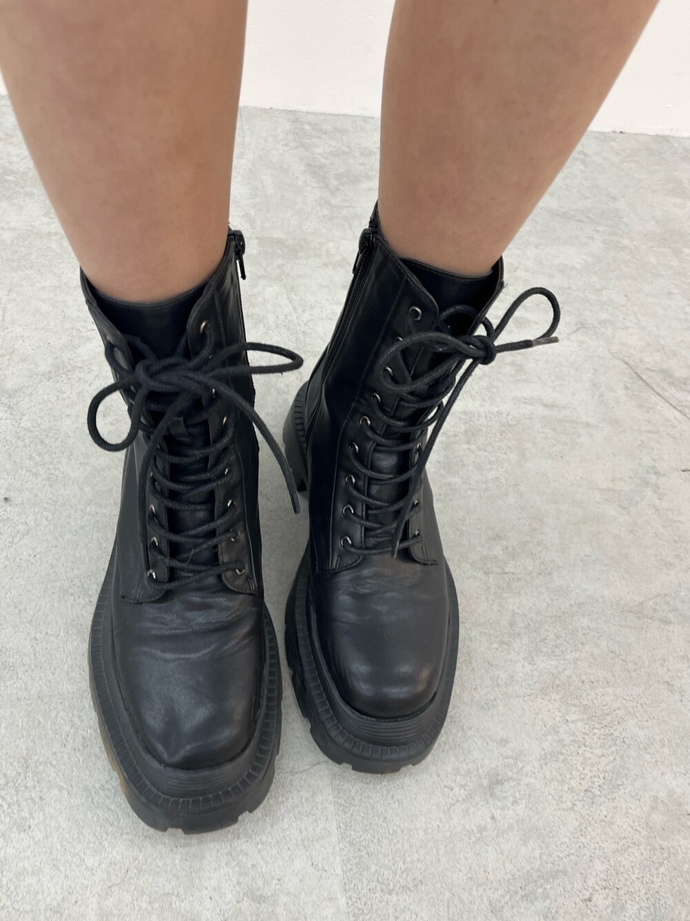 グレー系のハンドバッグ、ホワイト系のワンピース、ブラック系のブーツを着用したレディースの冬コーディネートの7枚目の写真