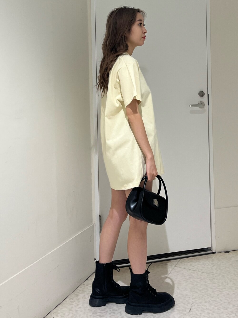 ブルー系のTシャツ/カットソー、ブラック系のハンドバッグ、ブラック系のブーツを着用したレディースの春コーディネートの4枚目の写真